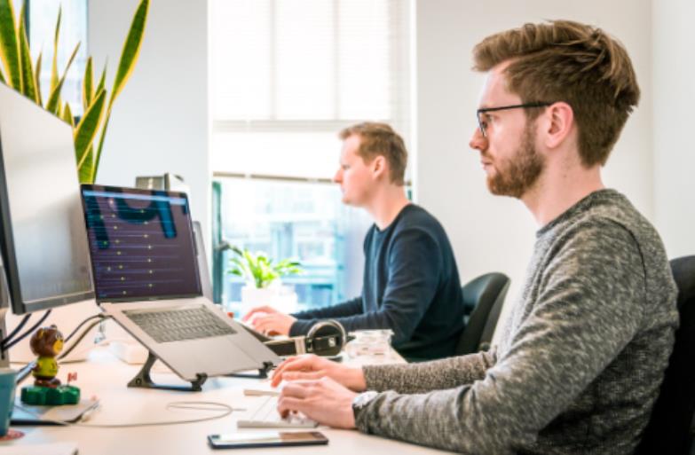Two employees at a desk using their computers to learn about the benefits of self service BI
